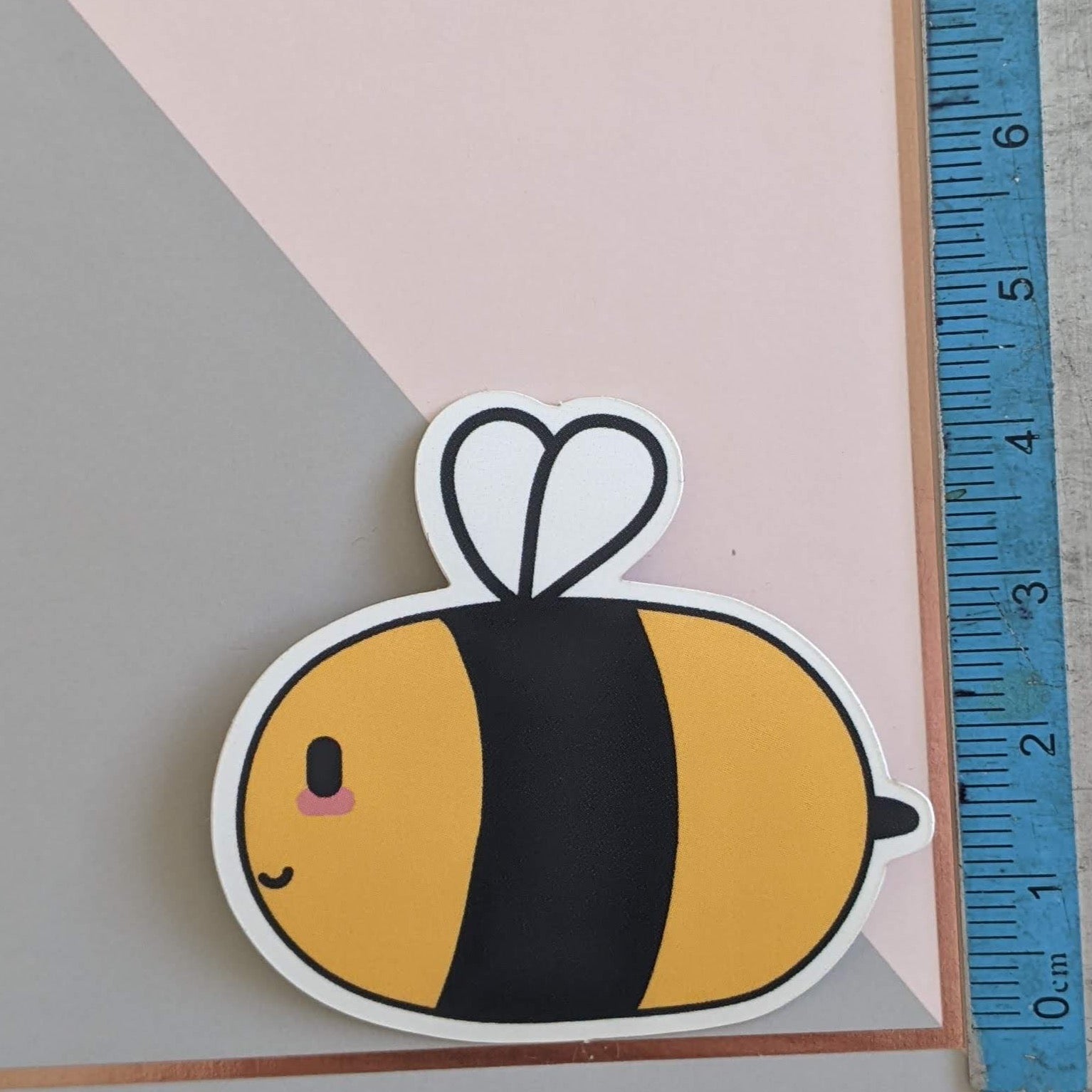 A close up of the bee sticker with a ruler showing scale, 4.5cm tall.