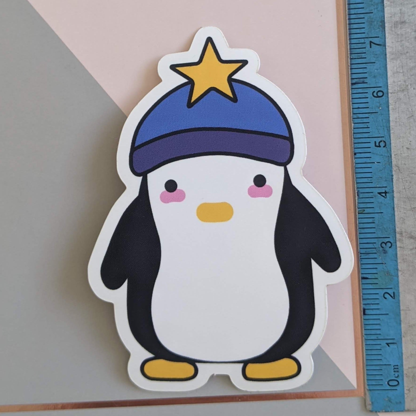 A close up of the penguin sticker with a ruler showing the scale at 7.5cm tall