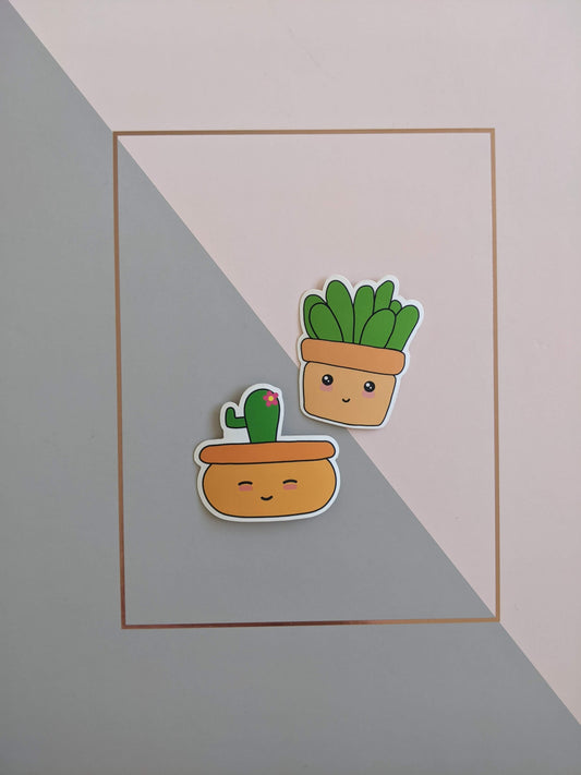 2 plant stickers on a pink and grey background. The top sticker has a square orange pot, a smiley face with blushed cheeks and chunky leaves sprouting out the top. The bottom stocker has a bowl shaped orange pot, a closed eyes smiley face with blushed cheeks and a cactus with a pink flower sprouting from the top.